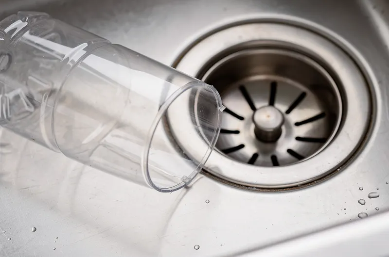 Garrafa PET cortada ao lado do ralo de uma pia de inox