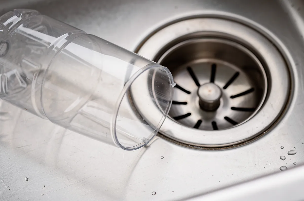Garrafa PET cortada ao lado do ralo de uma pia de inox