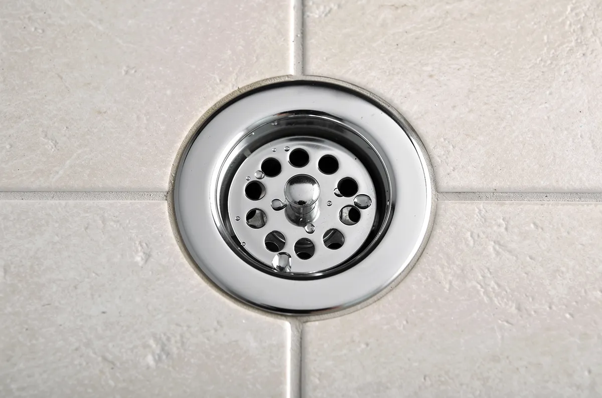 Ralinho redondo cromado no piso de um banheiro