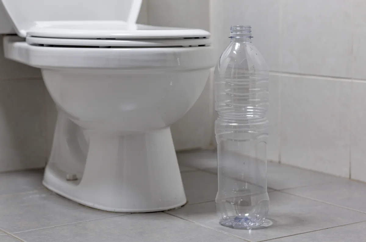 Garrafa PET ao lado de um vaso sanitário branco